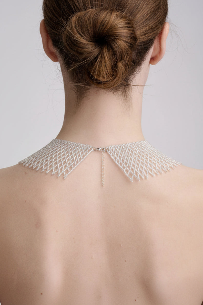 Person wearing a delicate lace garment on their back against a plain background