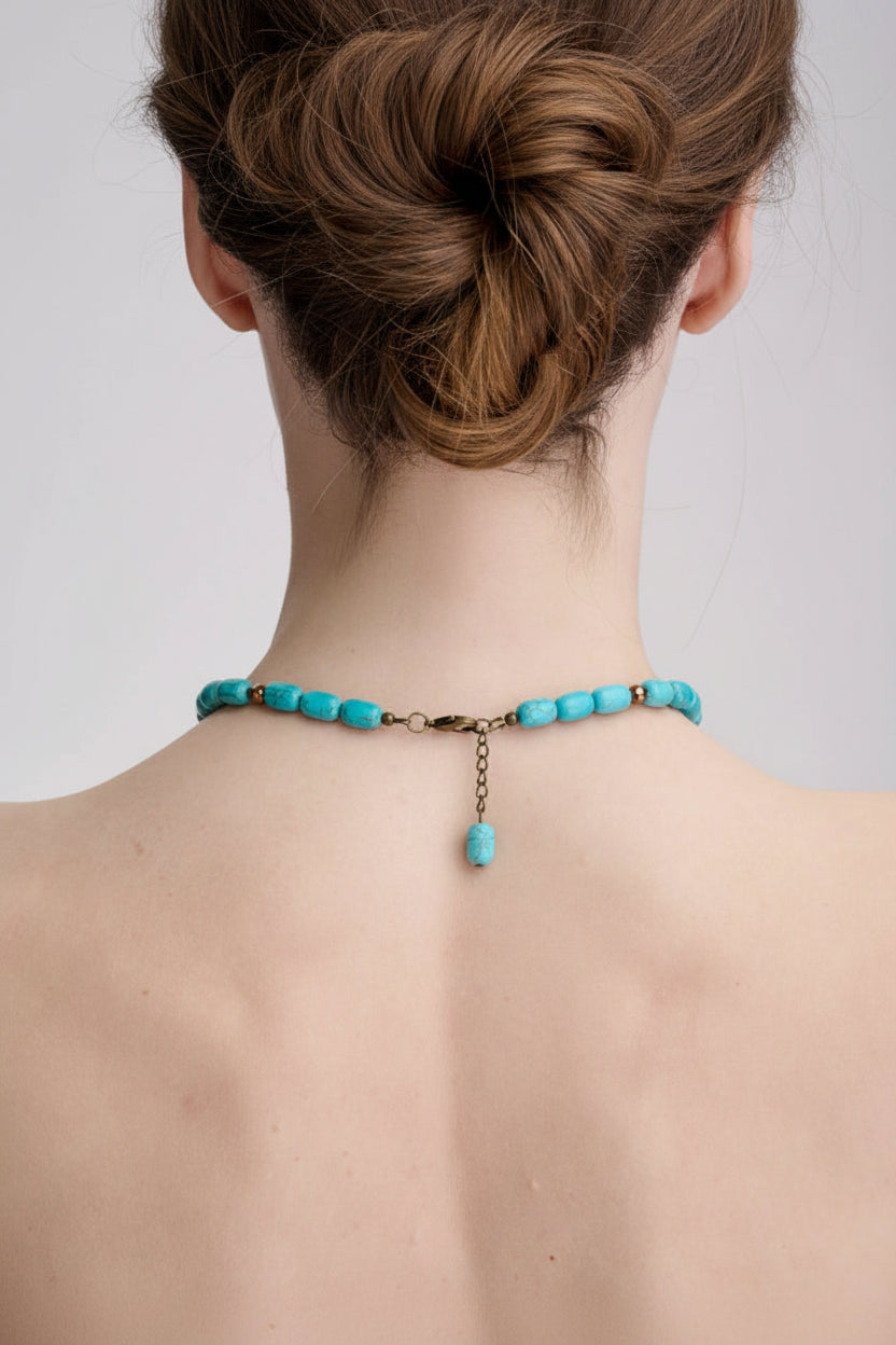 Turquoise beaded necklace on a person's neck against a plain background
