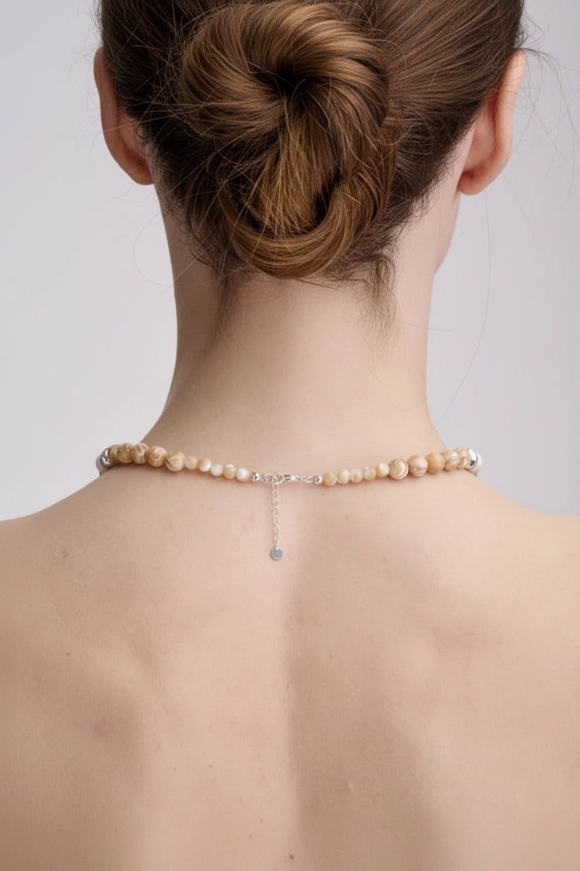 Pearl necklace worn by a person on a plain background