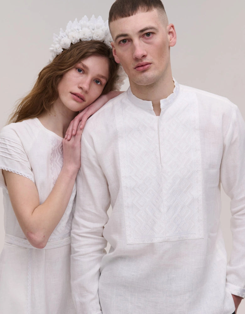Two people in white outfits posing against a plain background
