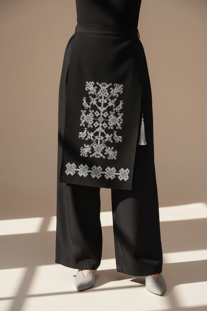 Black garment with white folk embroidery on a white background