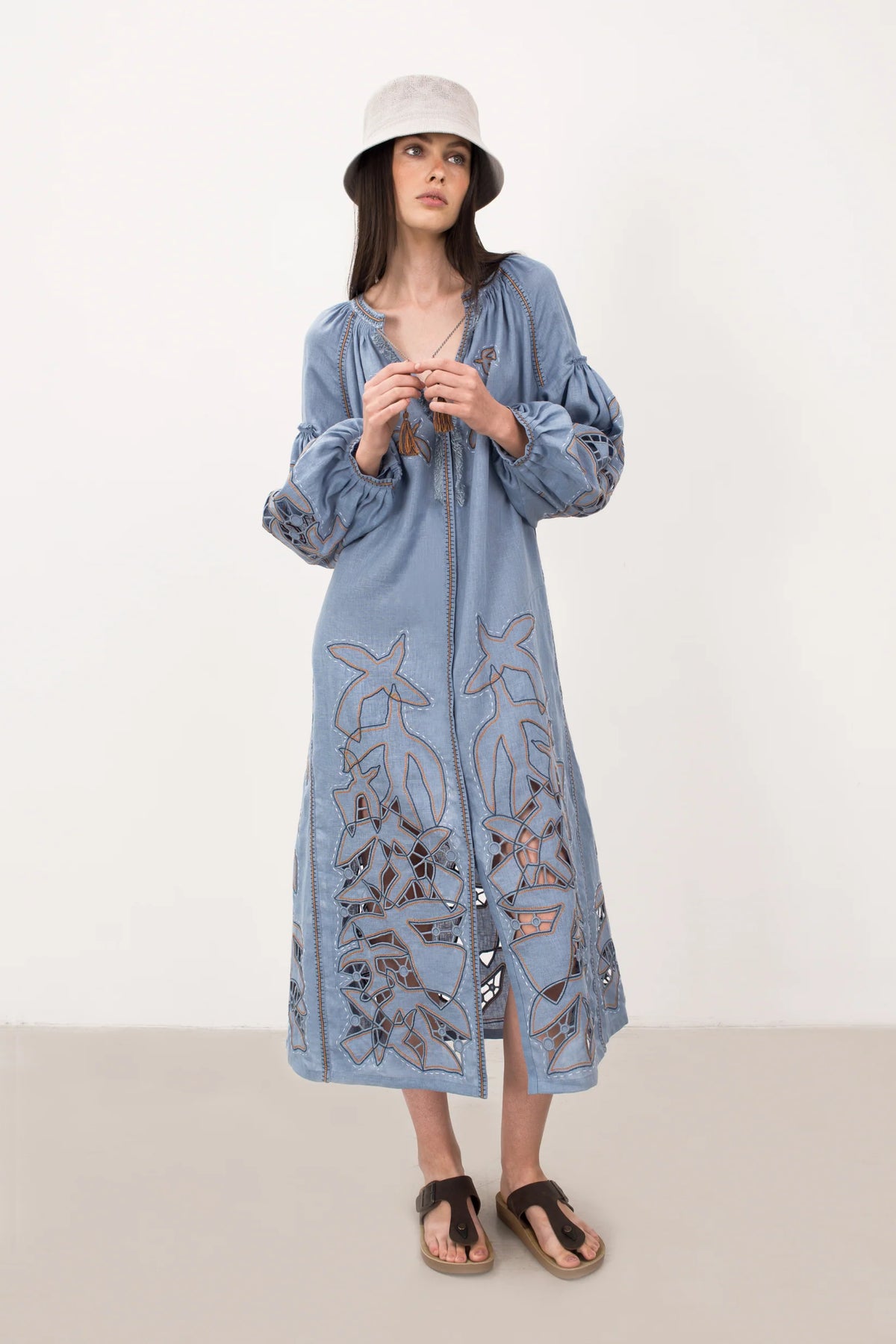 Woman wearing a long blue dress with ocean-themed patterns on a white background