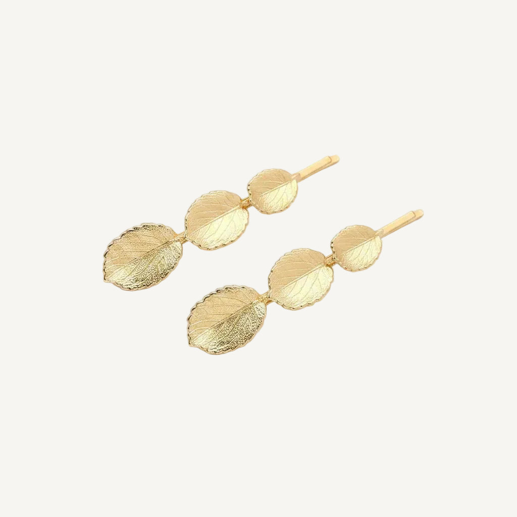 Gold leaf-shaped hairpins on a white background