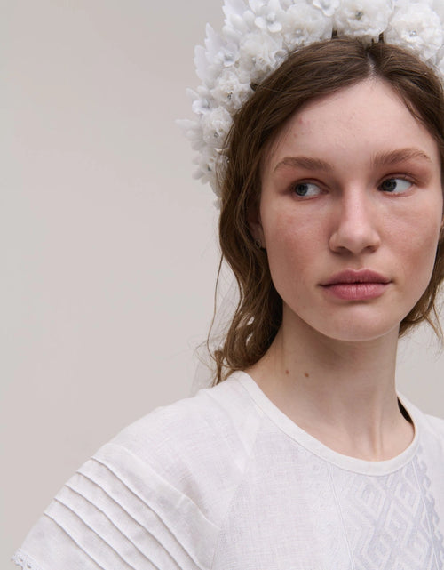 Woman wearing a white top with a neutral background
