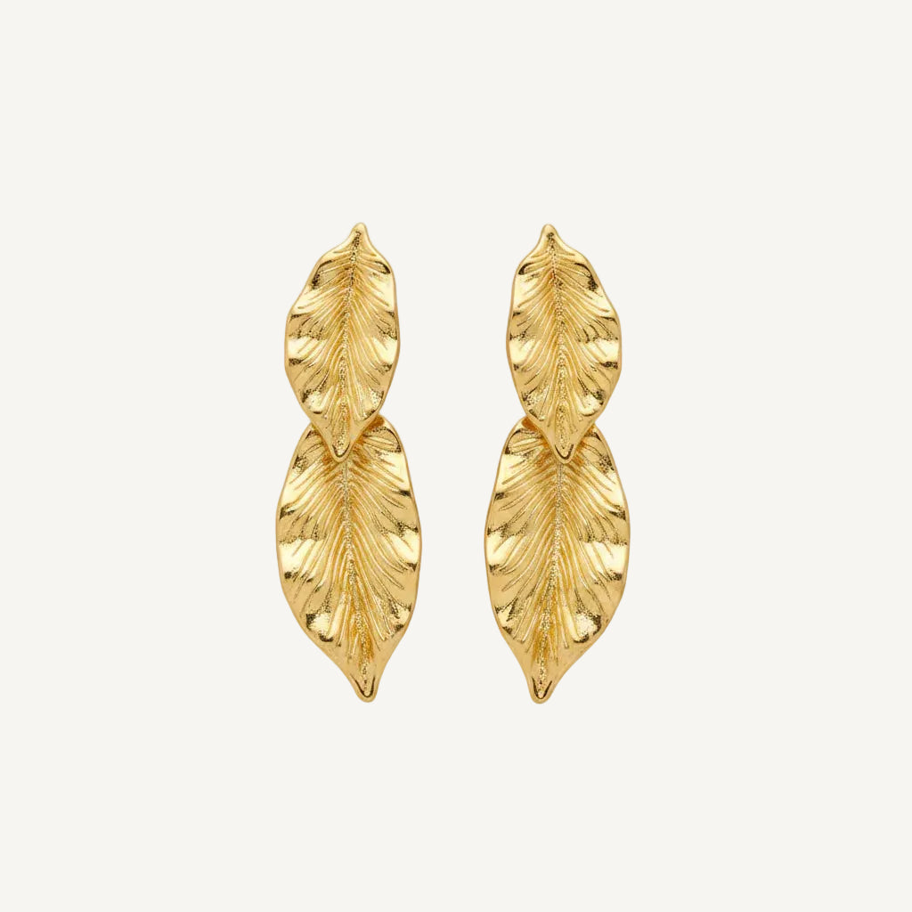 Gold leaf-shaped earrings on a white background