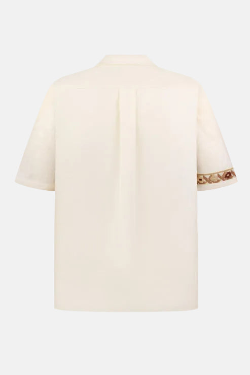 Beige t-shirt with embroidered trim on sleeves against a white background