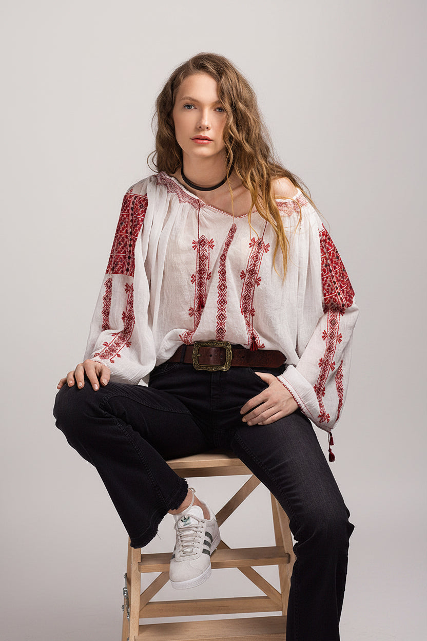 Woman wearing a white peasant  blouse with red embroidery,
