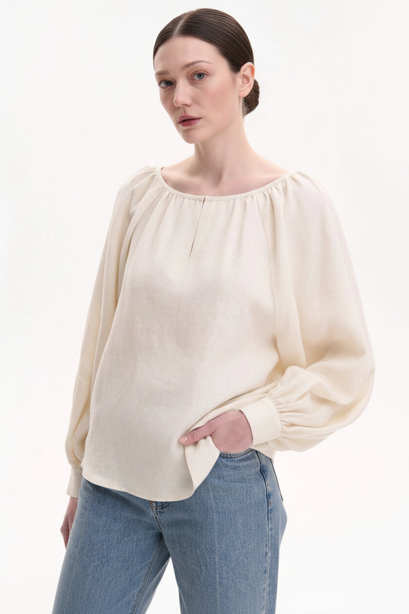 Woman wearing a beige blouse and blue jeans with a white background