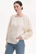 Woman wearing a beige blouse and blue jeans with a white background