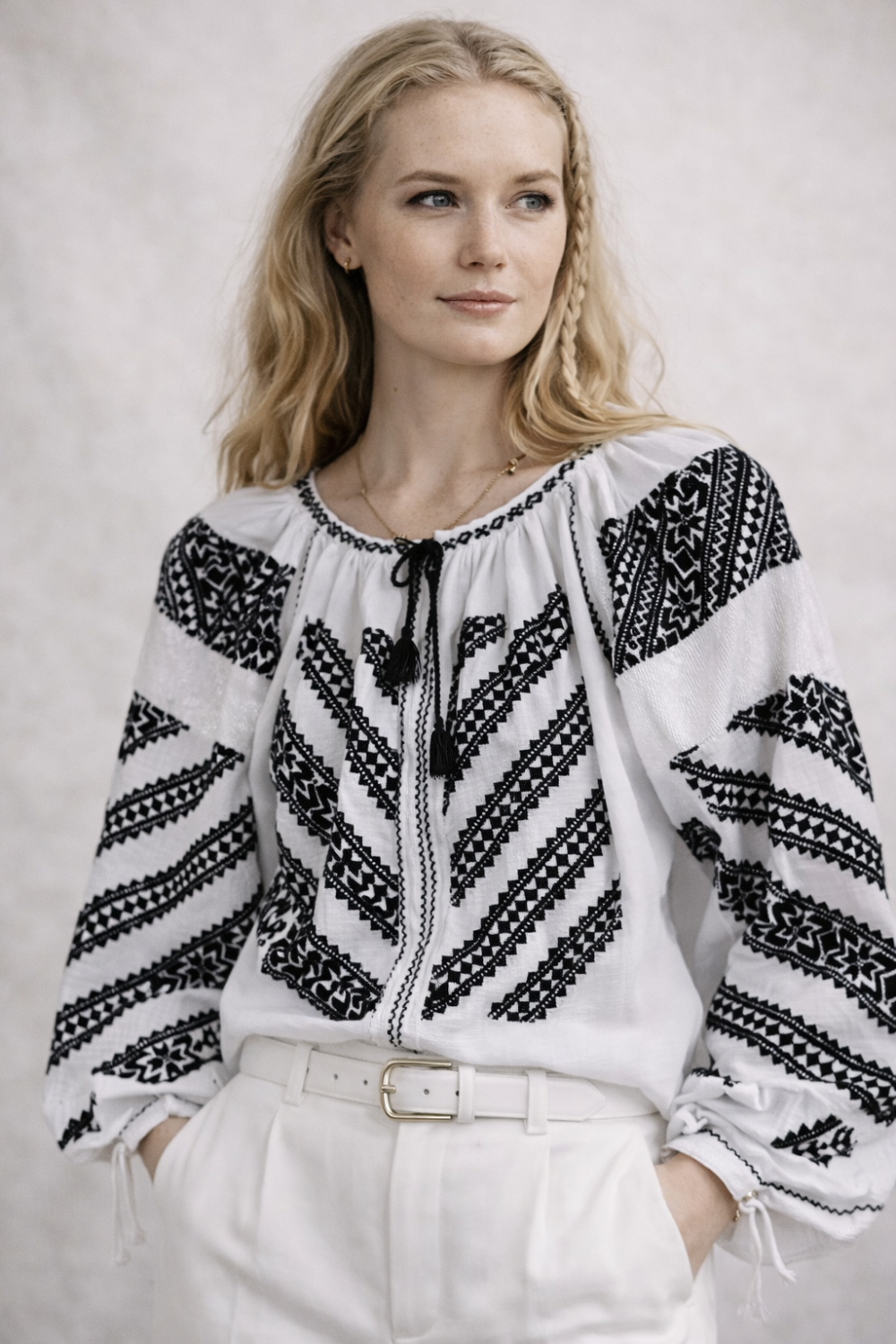 Woman wearing a black and white patterned blouse against a plain background