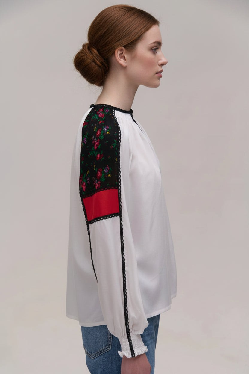 White blouse with embroidered sleeves on a plain background