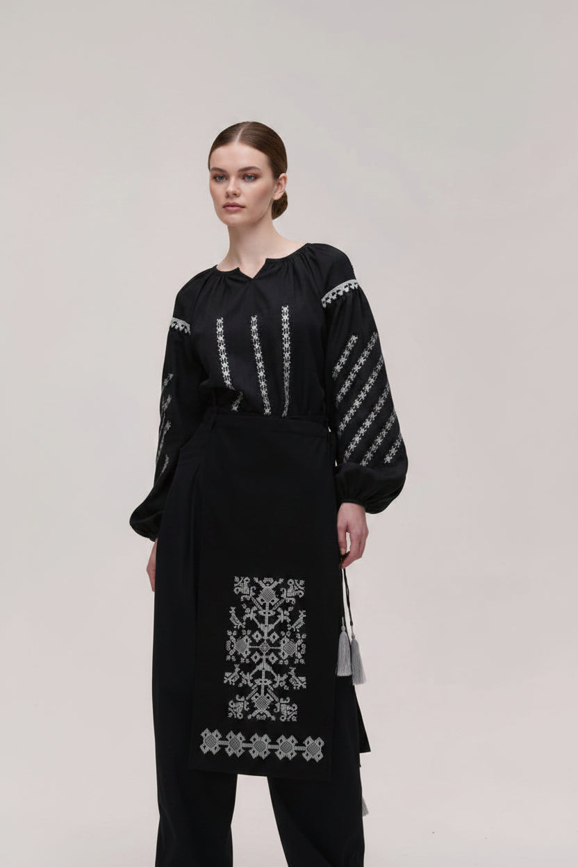Black outfit with white embroidery on a plain background