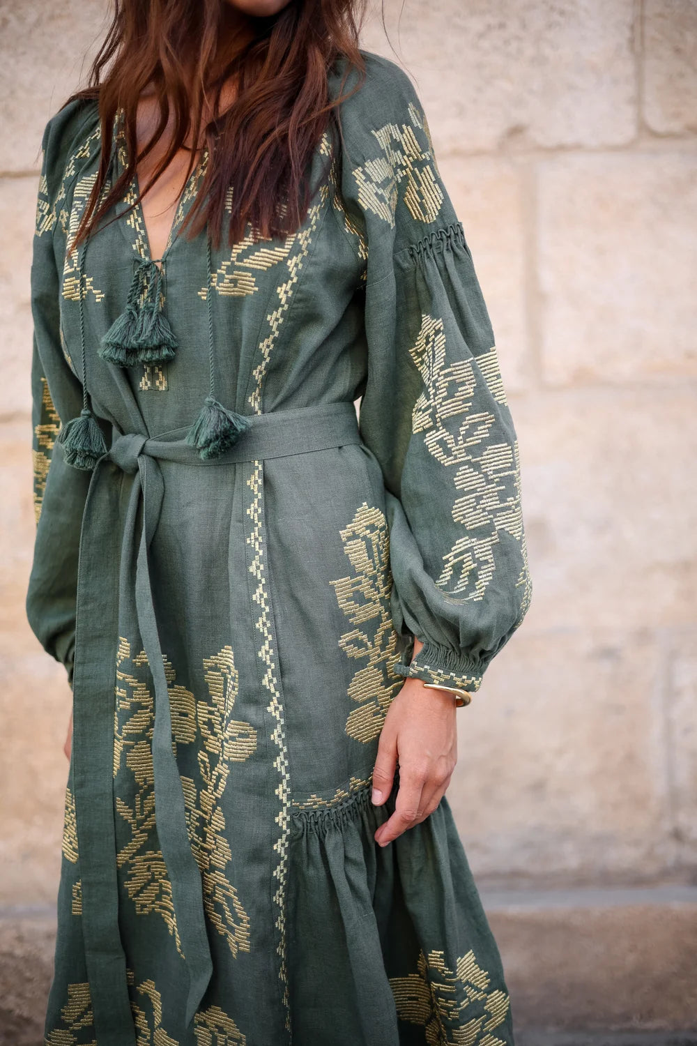 A woman ong-sleeved, tie-waist bohemian maxi dress in sage green with gold floral embroidery ANNABO
