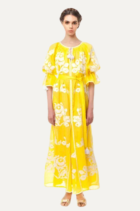 Woman wearing a yellow floral dress on a gray background