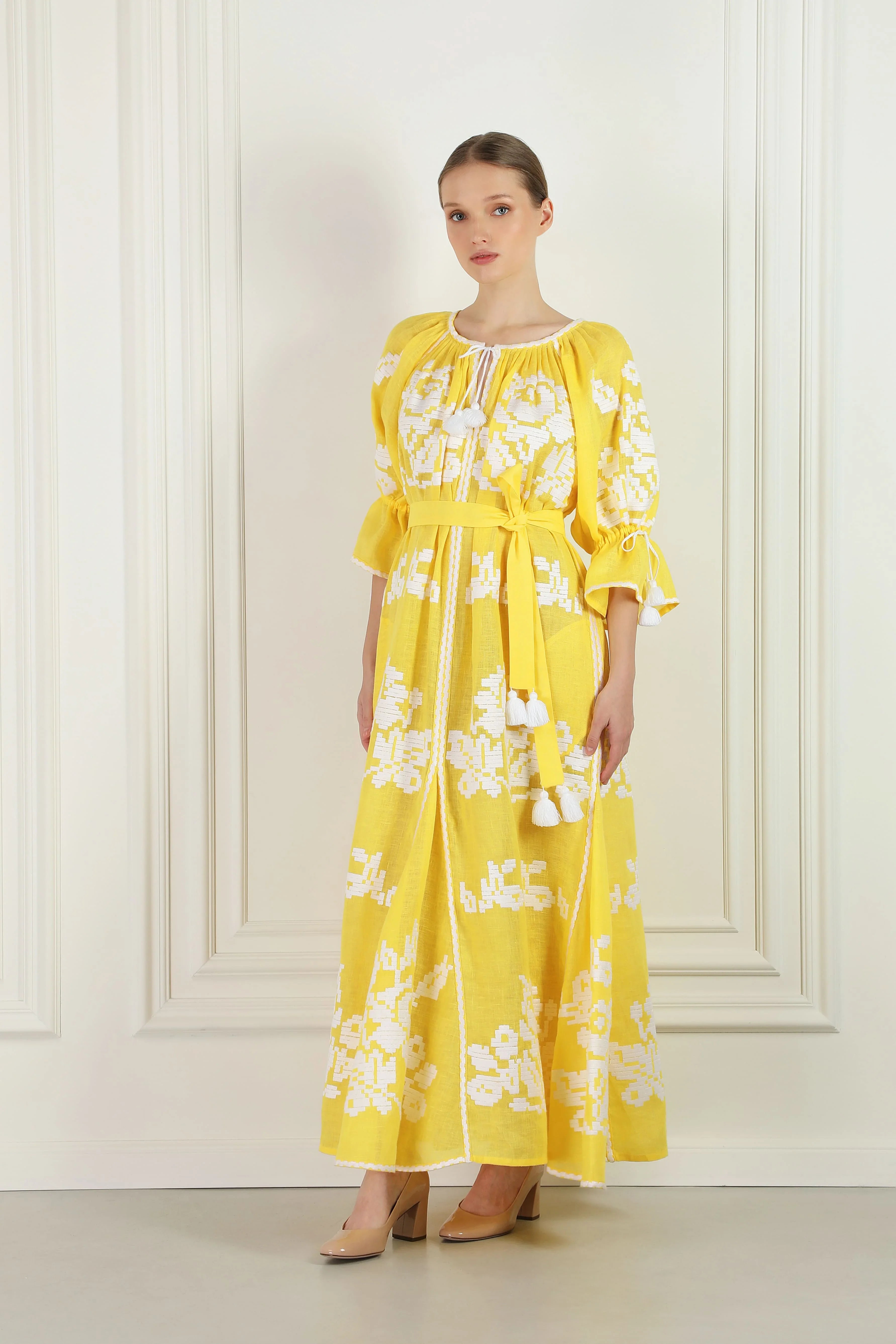 Woman wearing a yellow floral dress against a white background