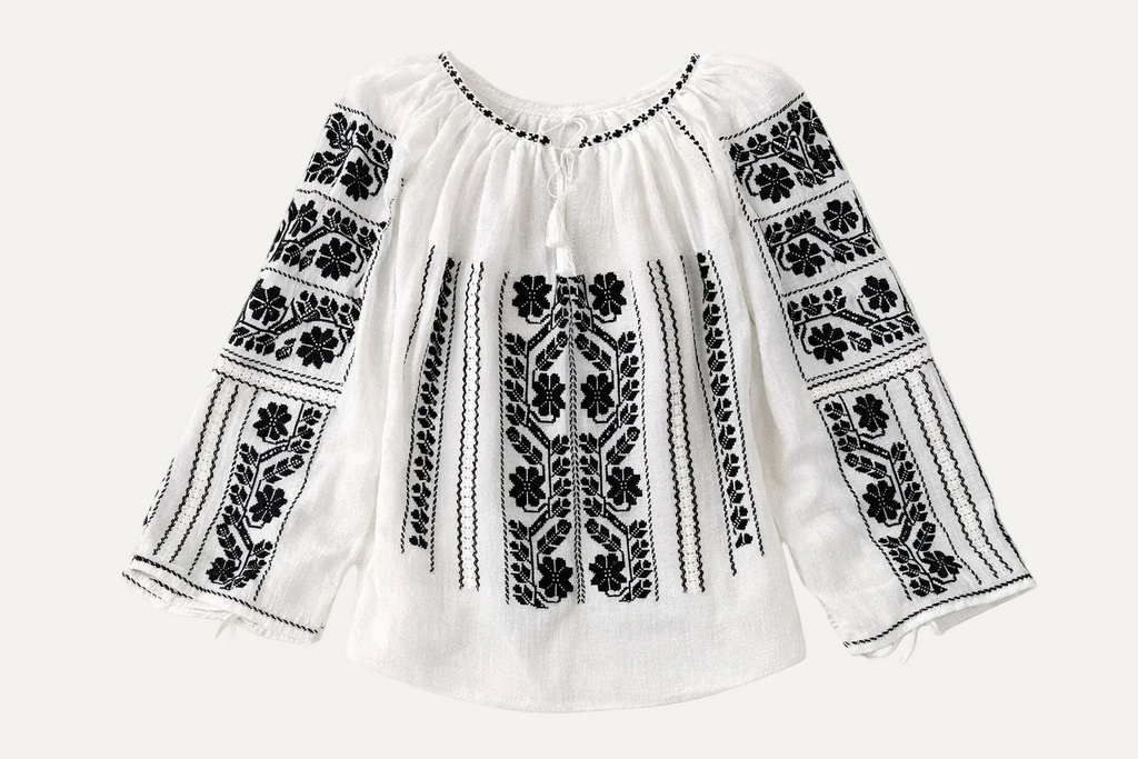 White blouse with black floral embroidery on a white background