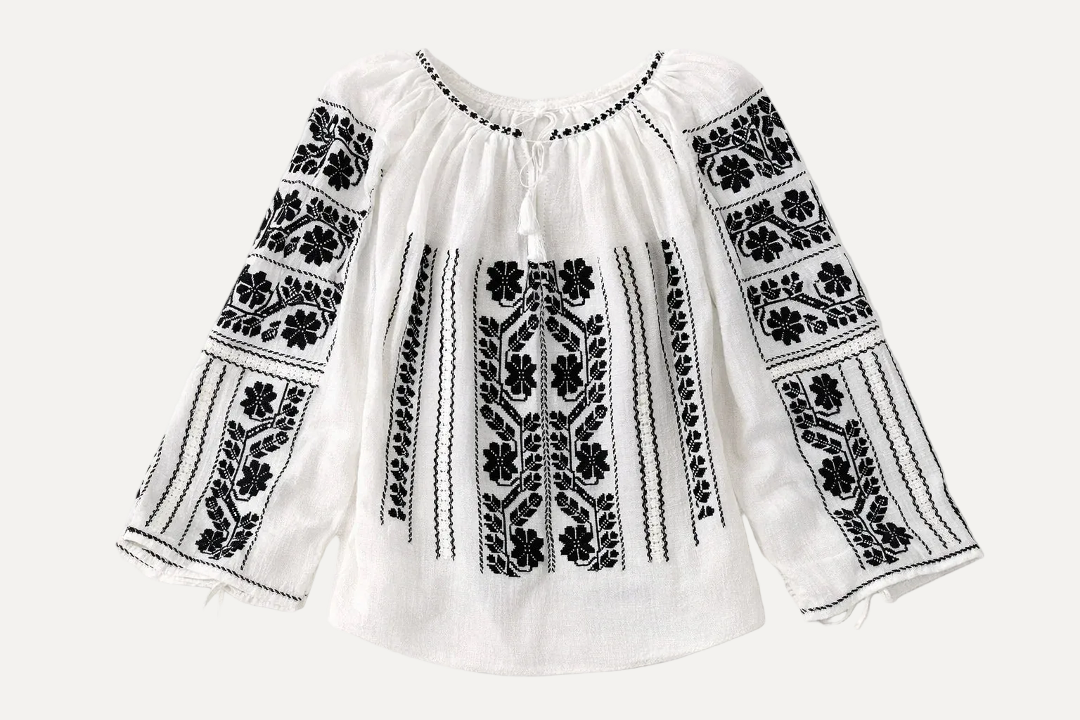 White blouse with black floral embroidery on a white background