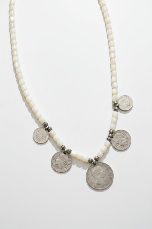 A beaded necklace with white round beads and several silver coin charms, traditional heritage jewlery