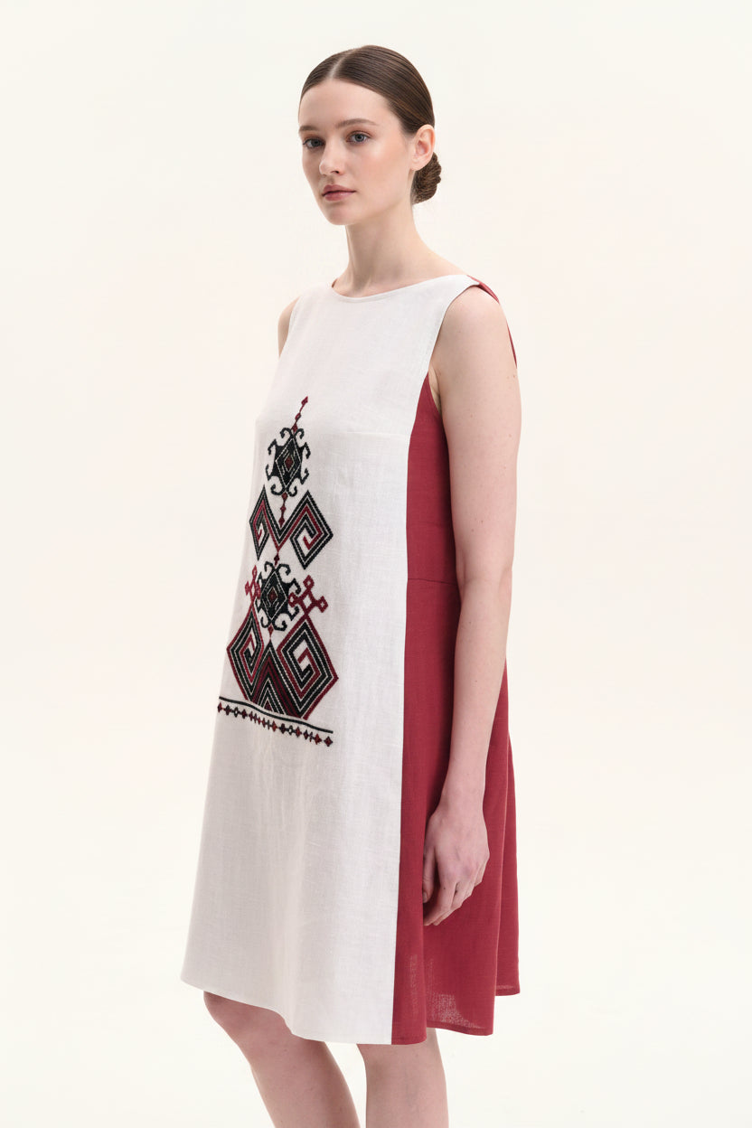 Woman wearing a white dress with red accents and geometric patterns on a white background