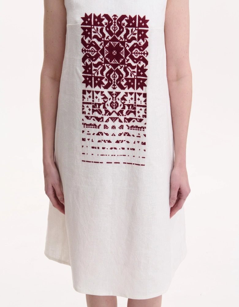 White dress with red geometric pattern worn by a person on a white background