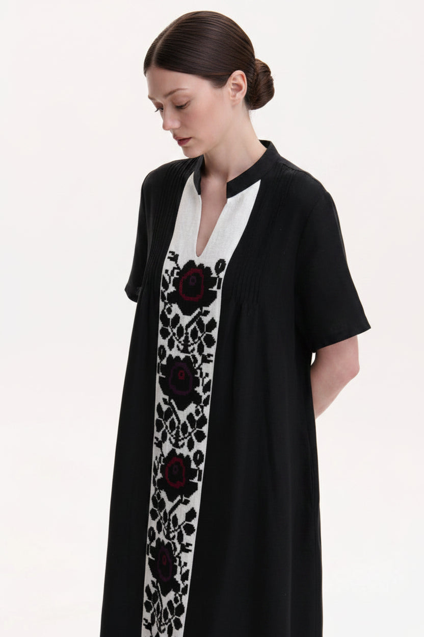 Black dress with a white panel featuring red floral embroidery on a plain background