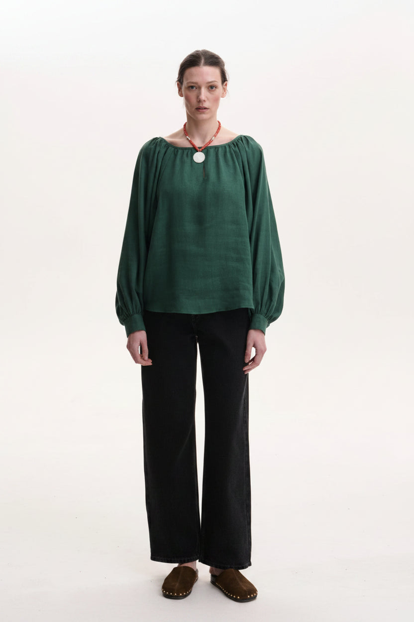Woman wearing a green top and black pants on a white background