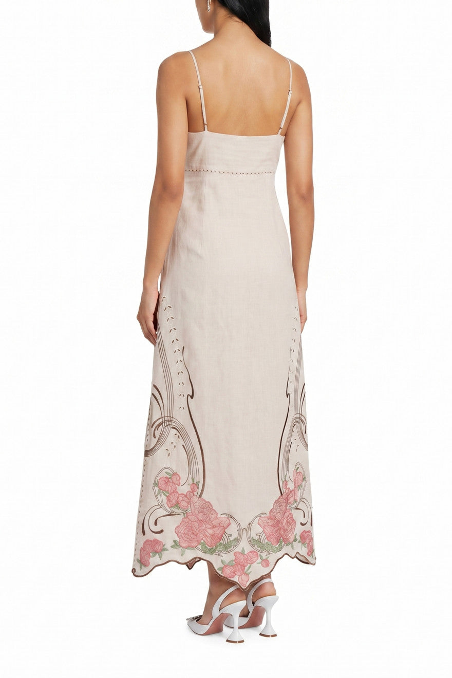 Woman wearing a beige dress with floral embroidery on a white background