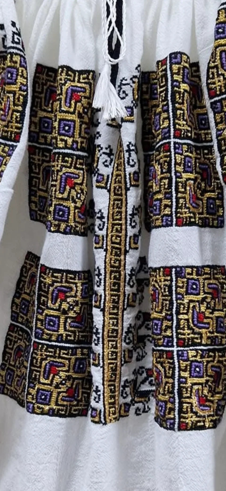 Traditional embroidered fabric with geometric patterns on a white background