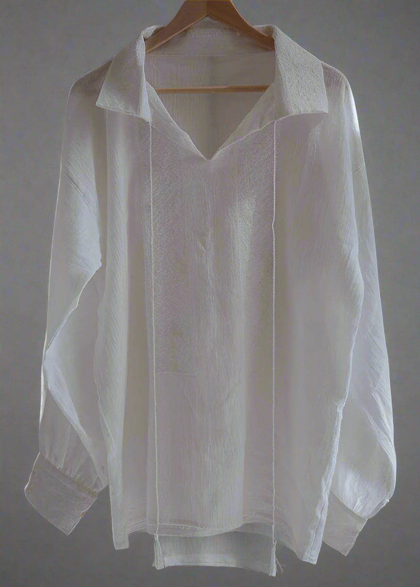 White shirt on a wooden hanger against a plain background