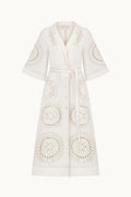 An off-white eyelet dress with a tie waist and decorative circular cutwork patterns, shown on a plain white background.
