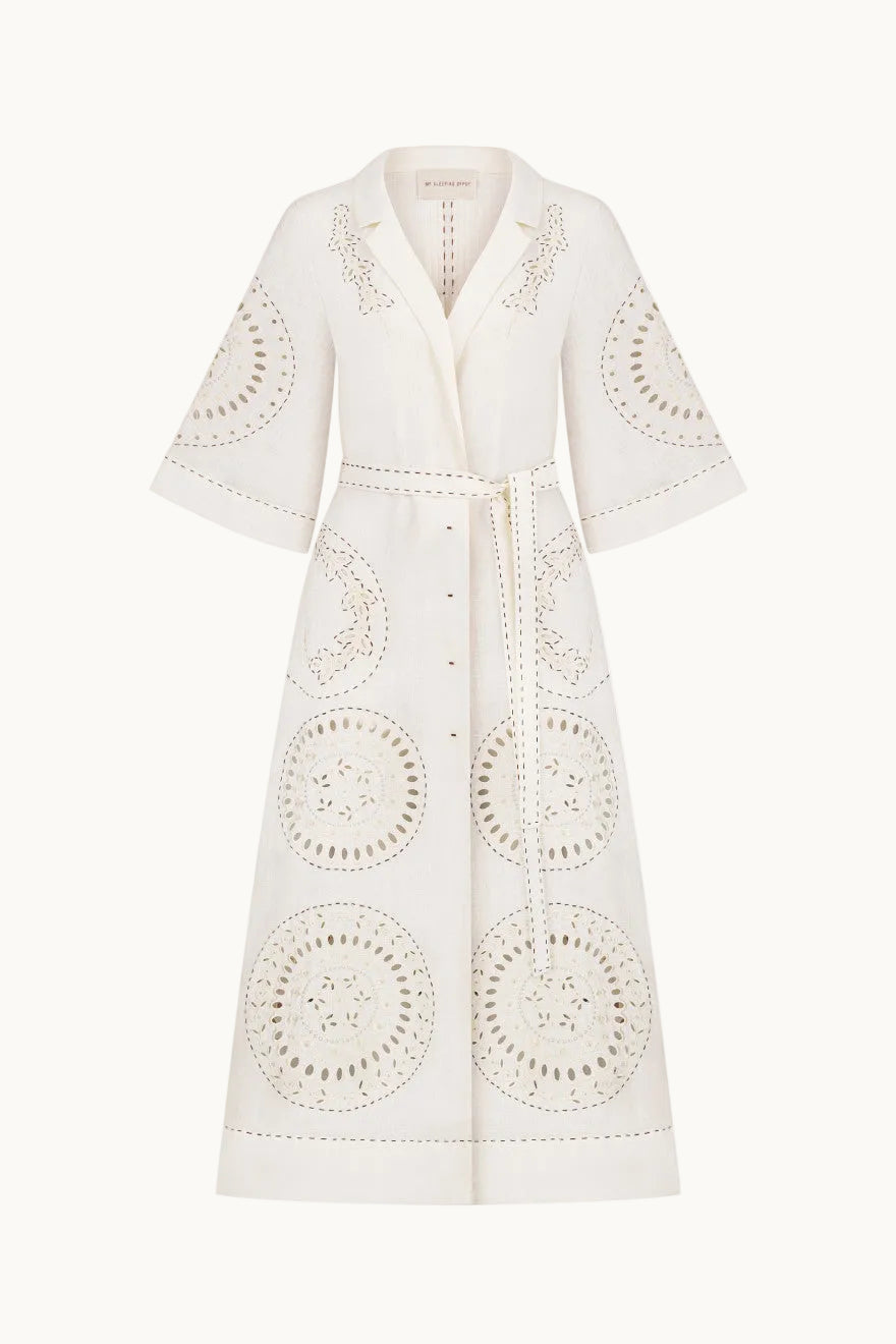 An off-white eyelet dress with a tie waist and decorative circular cutwork patterns, shown on a plain white background.