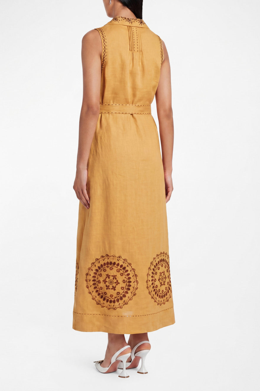 Woman wearing a mustard yellow dress with intricate embroidery on a white background