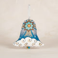 A handmade Christmas bell ornament featuring a blue and gold starburst design, white clouds with gold outlines, and a small hanging bead at the bottom.